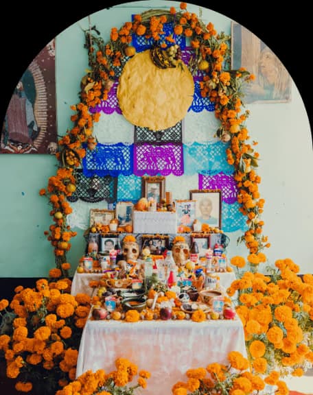 Traditional Día de Muertos altar with colorful decorations, candles, and offerings